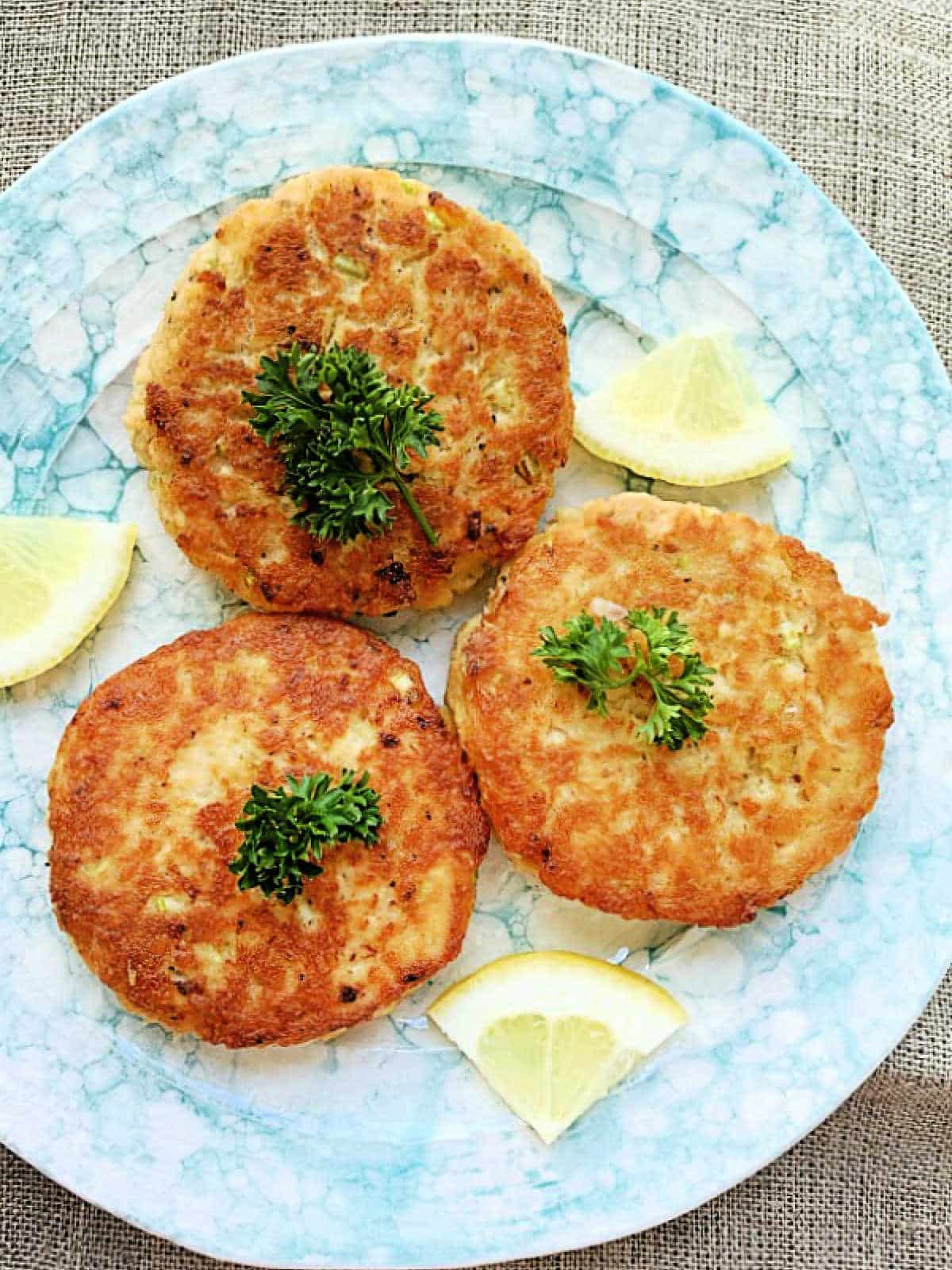three plated salmon patties garnished with fresh parsley
