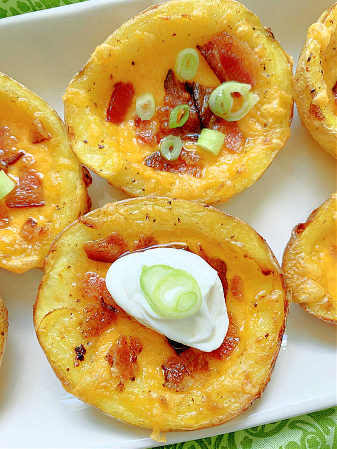 perfect air fryer potato skins on a platter, garnished with sour cream and green onions