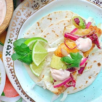 baja fish taco plated with fresh lime wedges and cilantro