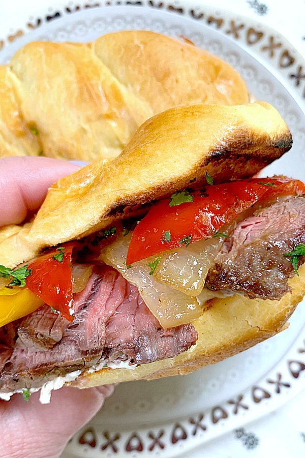 holding a grilled steak sandwich