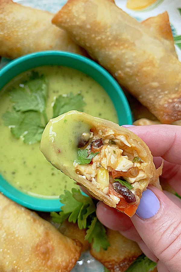 dipping a southwestern egg roll into avocado salsa