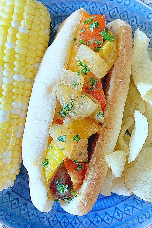 loaded air fryer brat on a plate with corn on the cob and potato chips