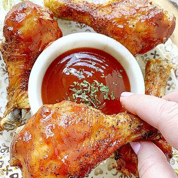 holding an air fryer chicken leg - ready to dip in bbq sauce