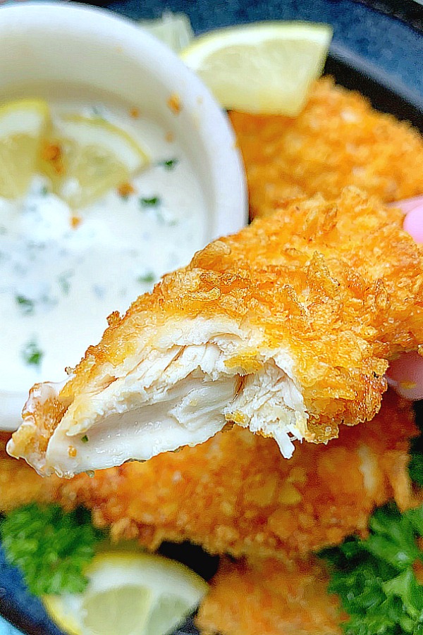 taking a bite out of a chicken tender dipped in ranch dressing