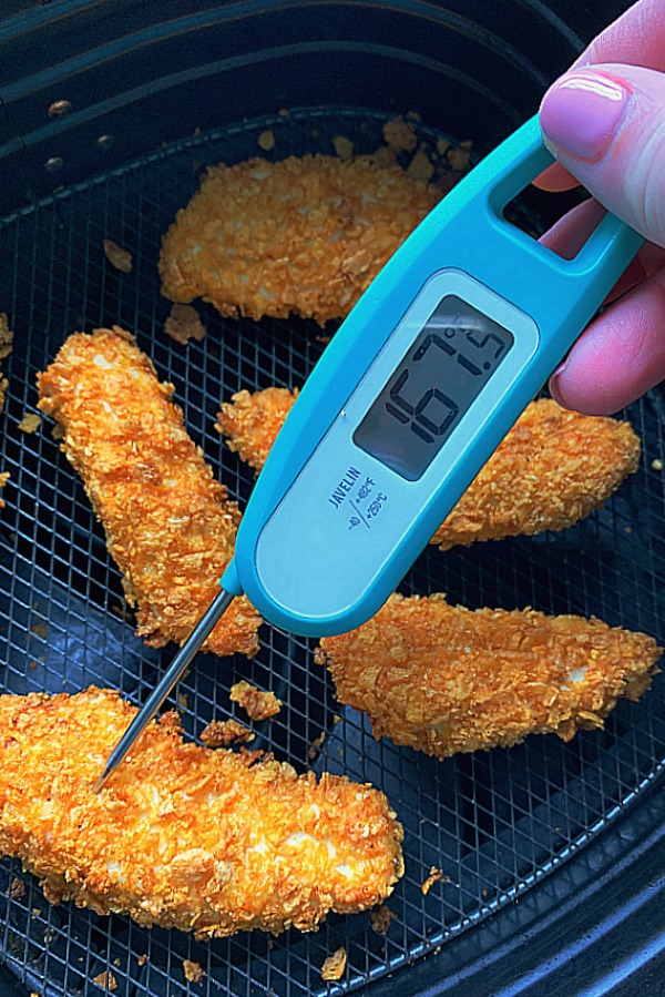 checking the temperature of cooked chicken tenders in the air fryer