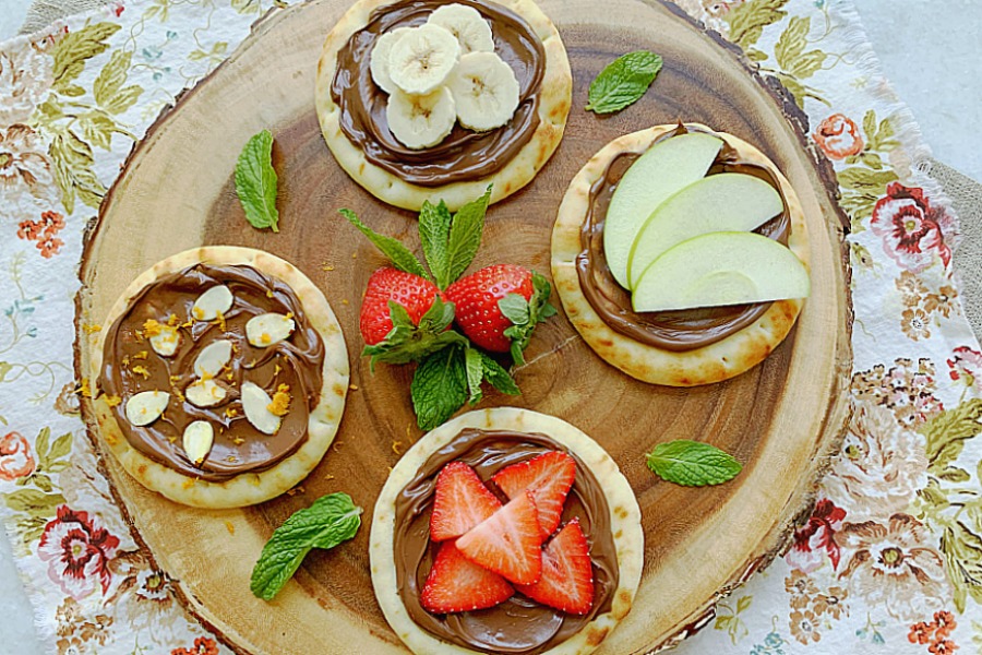 wooden charger topped with four different nutella pizzas