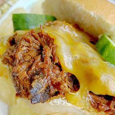 taking a bite of a pulled beef sandwich