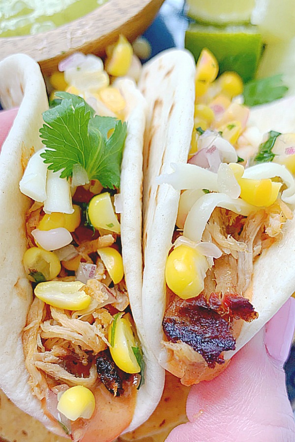 holding two pulled pork tacos, getting ready to take a big bite