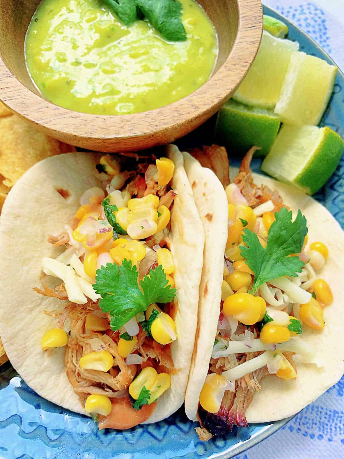 two plated pulled pork tacos with a side of guacamole