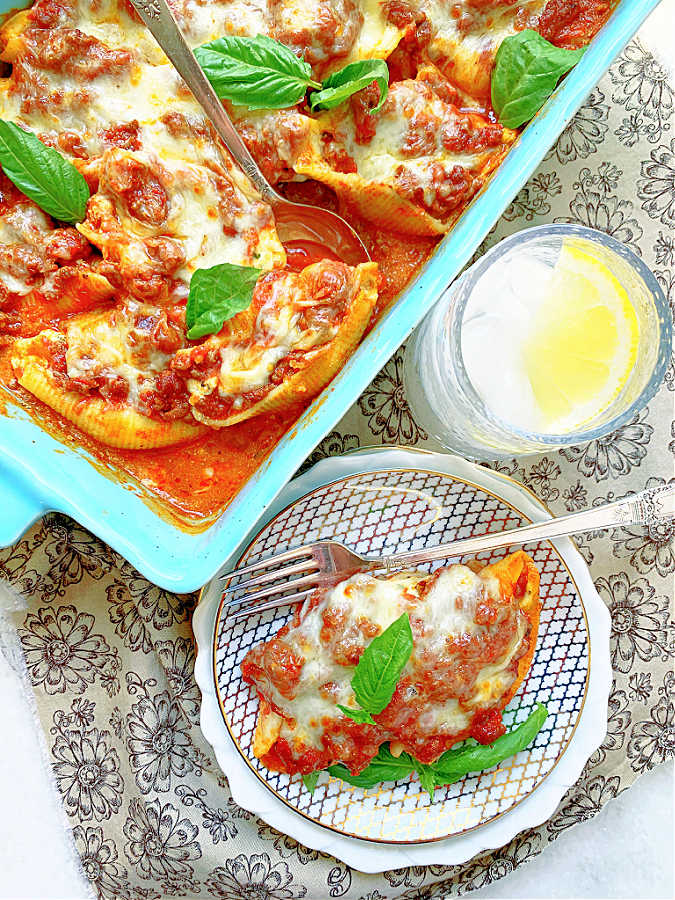 baked dish of stuffed shells with a small plate serving alongside