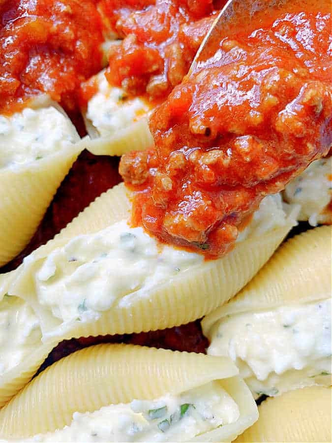 topping the stuffed shells with meat sauce