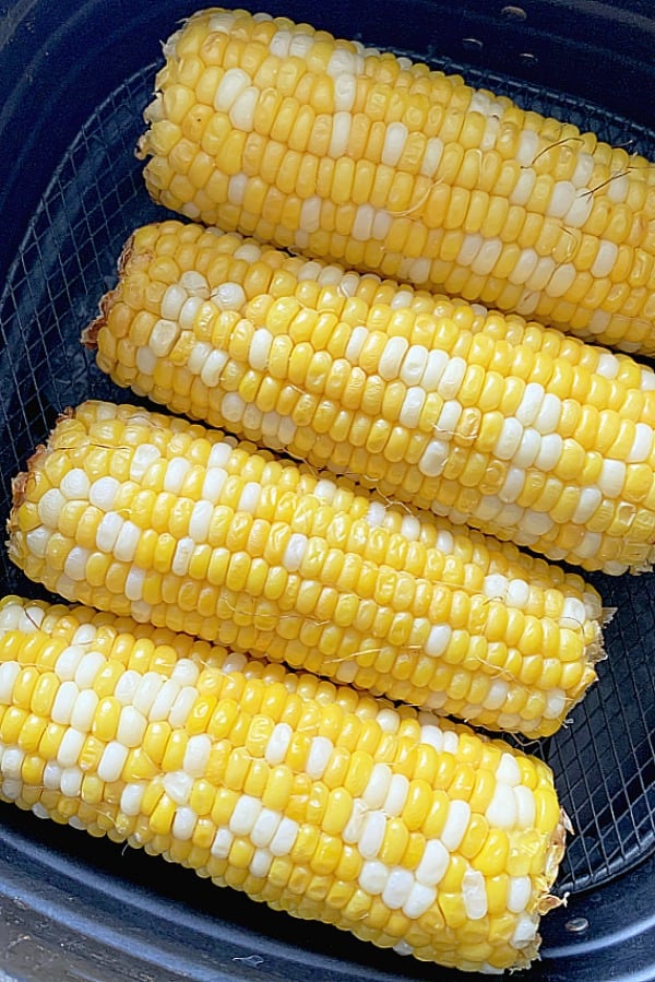 four ears of corn on the cob in the air fryer basket