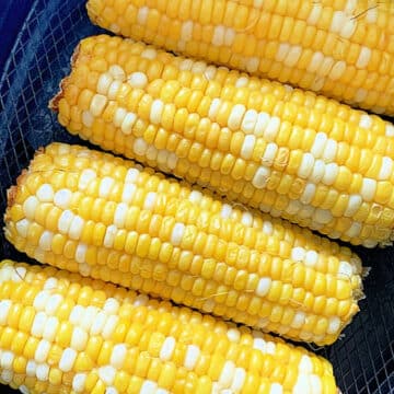 four cooked ears of corn in the air fryer basket
