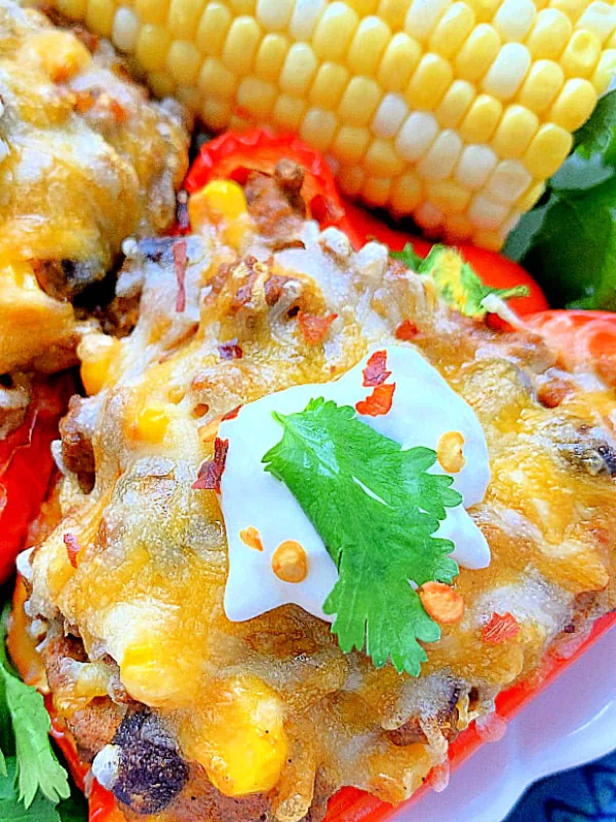 air fryer stuffed red bell pepper plated with an ear of corn on the cob