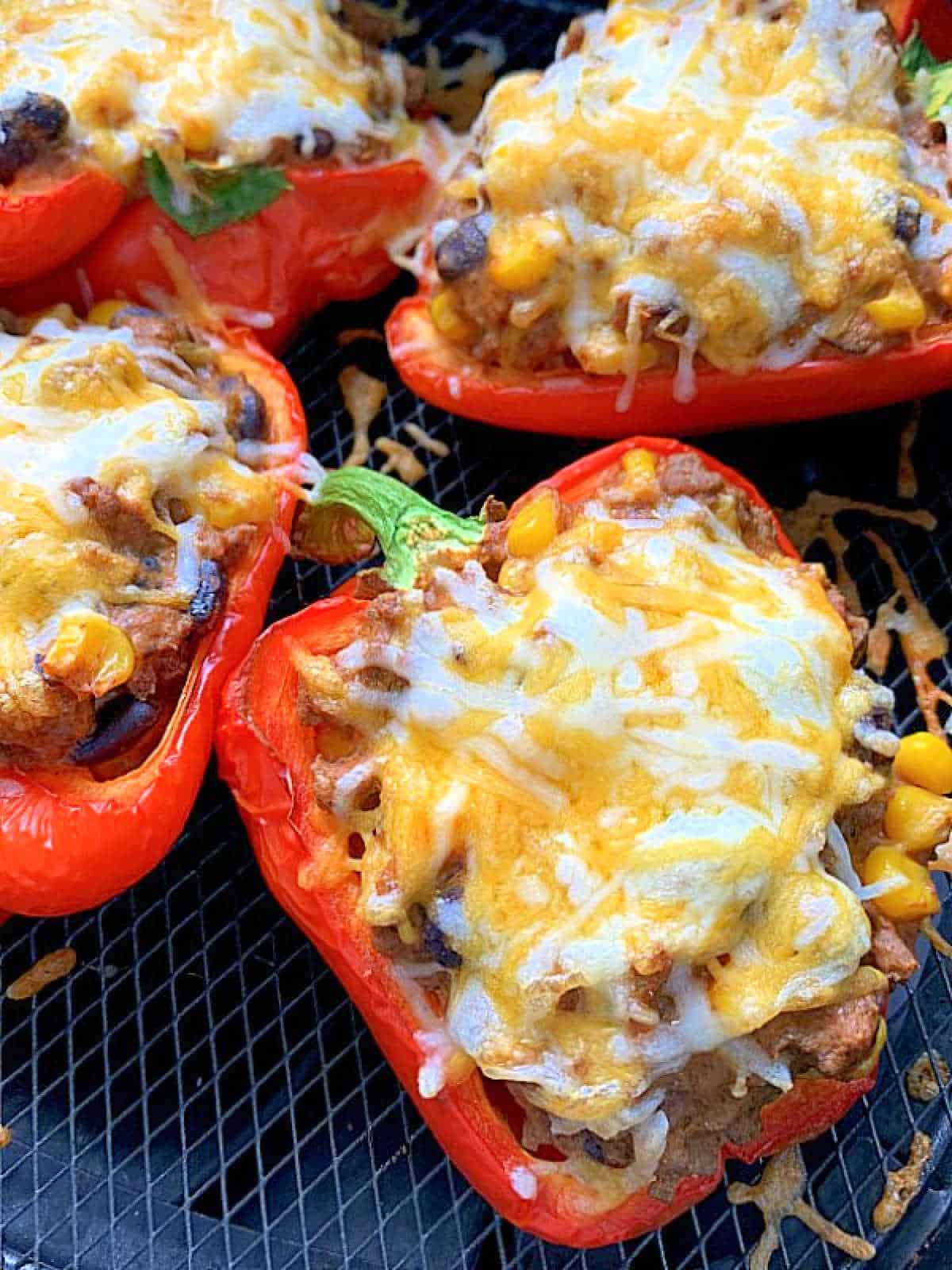 stuffed peppers topped with melted cheese in the air fryer basket
