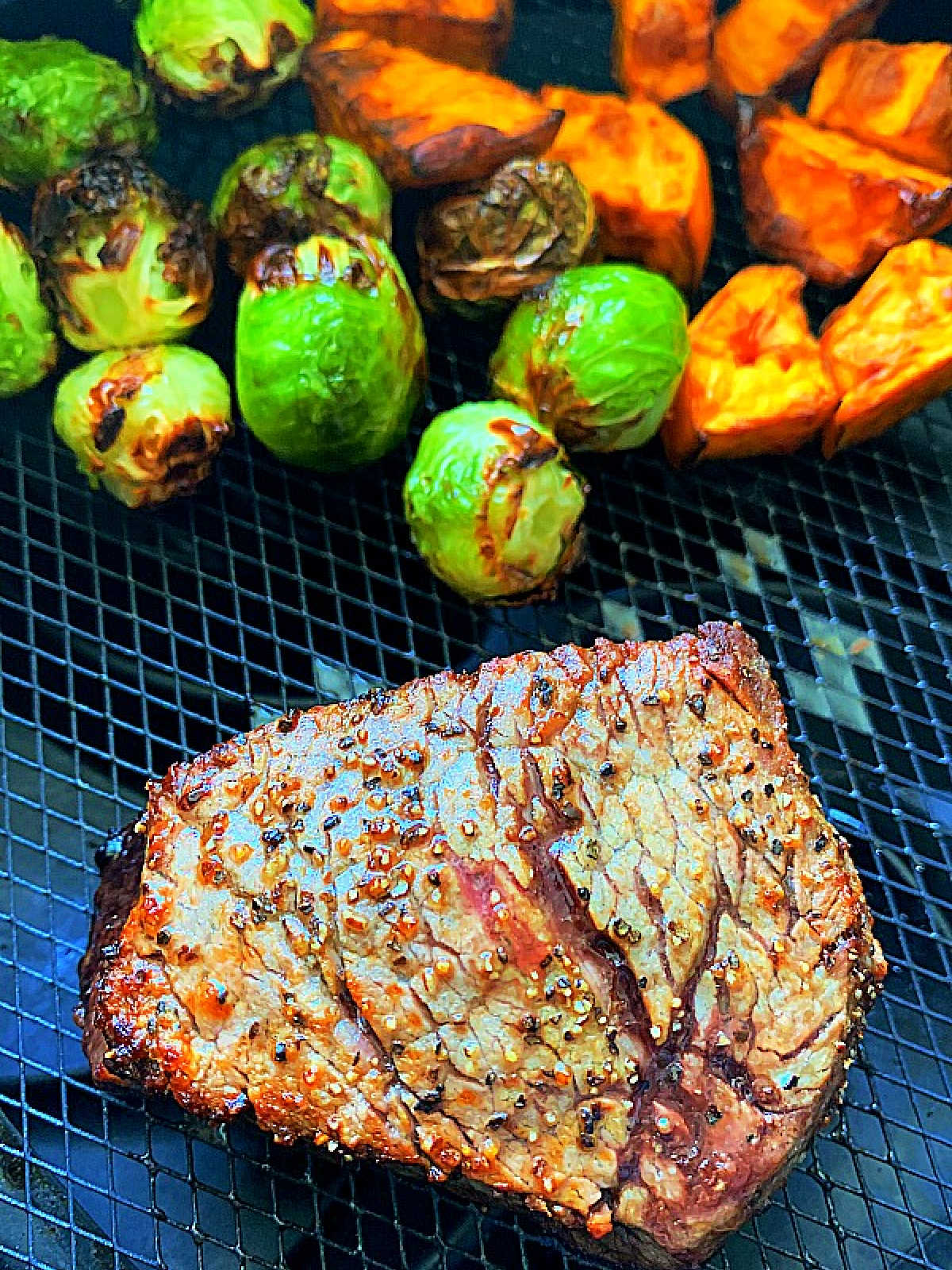 cooked filet mignon, brussels sprouts and sweet potatoes in the basket of the air fryer