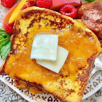 slices of buttermilk french toast topped with peach syrup and slices of butter
