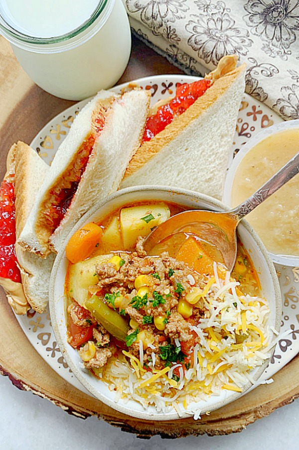 campfire stew in a bowl with peanut butter and jell sandwich on the side