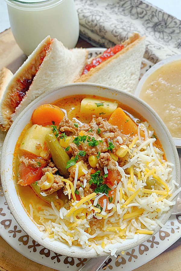campfire stew in a bowl with peanut butter and jelly sandwich on the side
