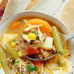 dipping a spoon into a bowl of campfire stew