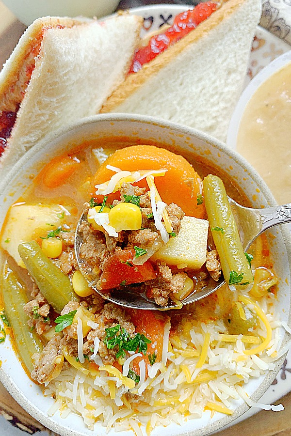 dipping a spoon into a bowl of campfire stew