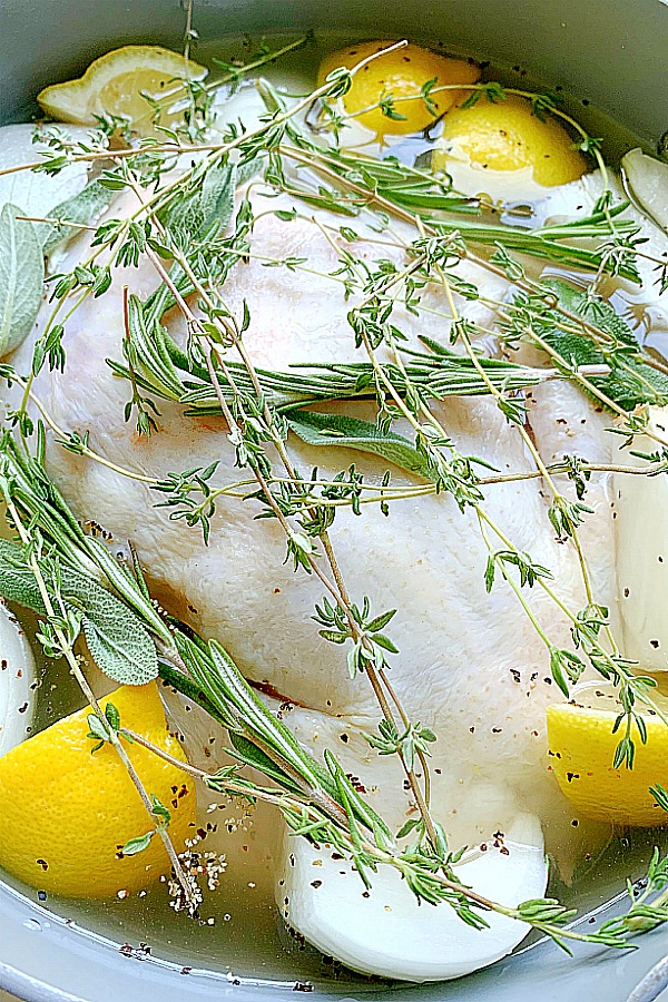 whole chicken in a pot with herbs and lemon