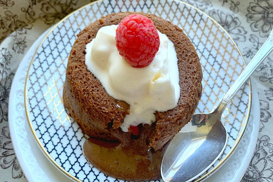 air fryer lava cake on a plate topped with vanilla ice cream and a fresh raspberry