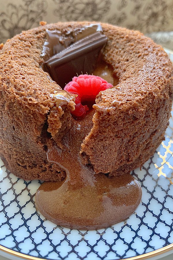 side view of air fryer lava cake with chocolate spilling onto plate