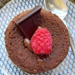 overhead shot of lava cake on plate topped with chocolate and a raspberry