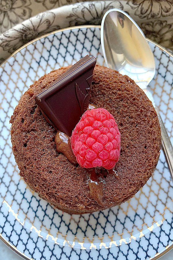 overhead shot of lava cake on plate topped with chocolate and a raspberry