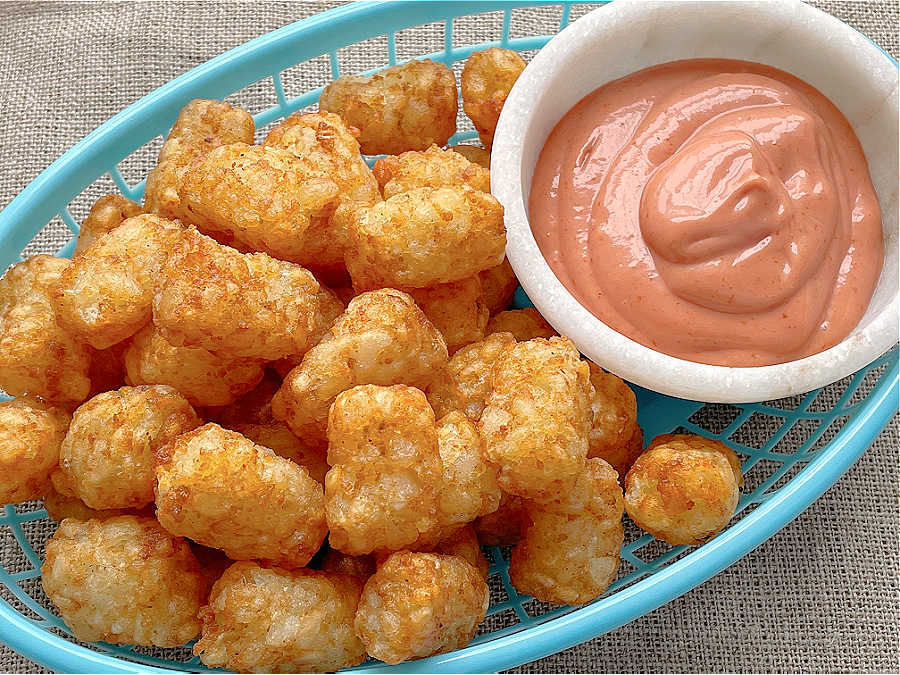air fryer tater tots in a basket with fry sauce on the side