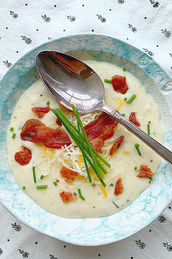 a bowl of easy baked potato soup topped with chives and bacon