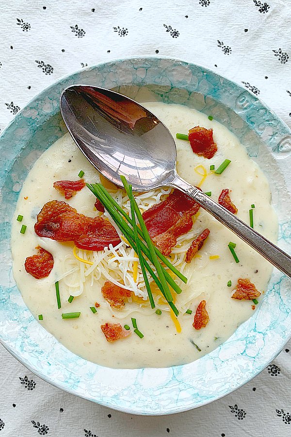 a bowl of easy baked potato soup topped with chives and bacon