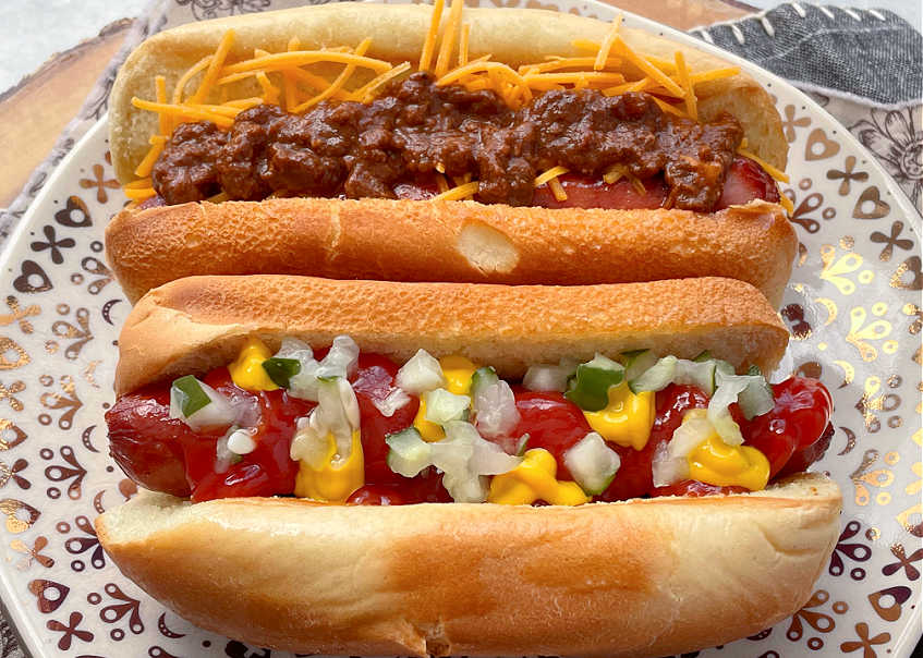 two air fryer hot dogs on a plate topped two different ways