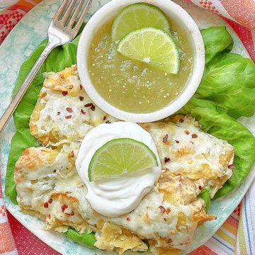 green chicken enchiladas on a plate topped with sour cream