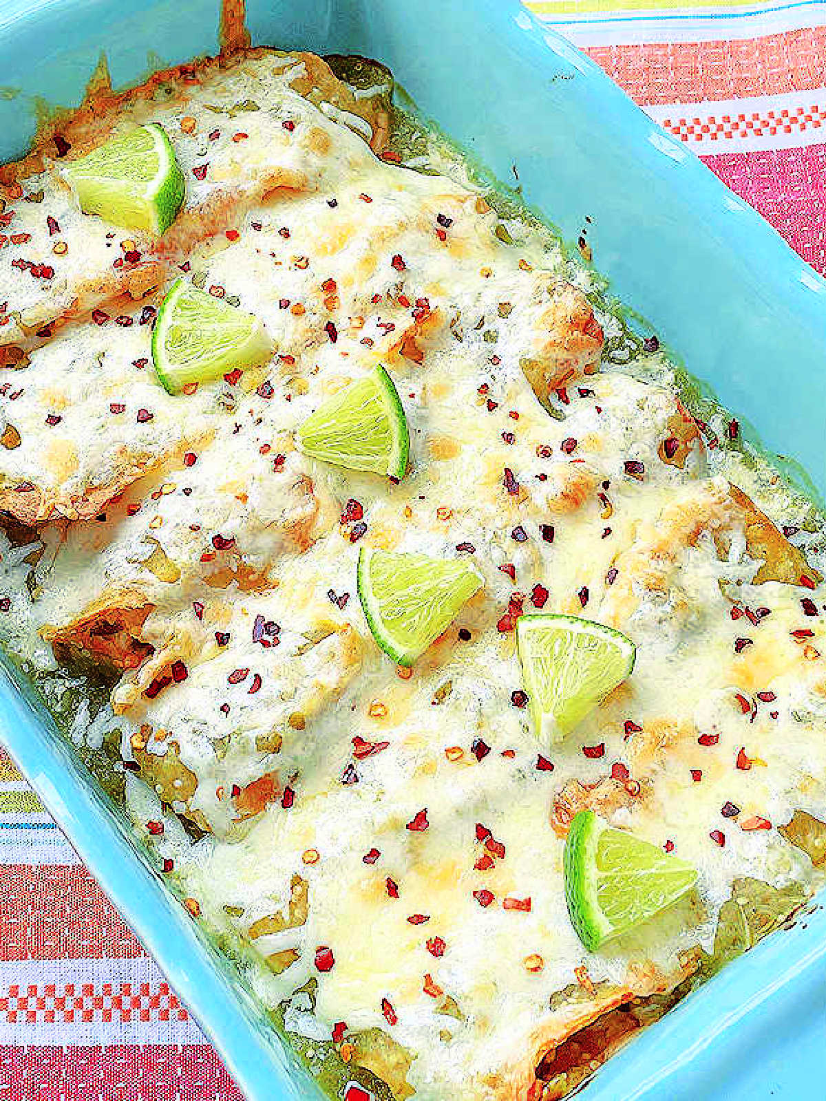 a full pan of enchiladas smothered with melted cheese and garnished with lime slices