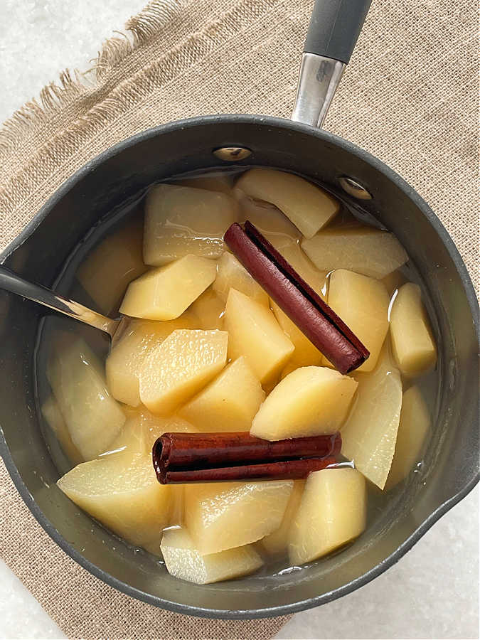stewed pears in the cooking pot with cinnamon sticks