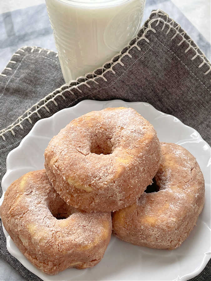 air fryer donuts stacked on a plate with a glass of milk on the side