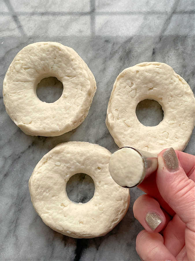 cutting holes in biscuit dough to make donuts