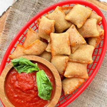 a red snack basket filled with air fryer pizza rolls and a small bowl of marinara sauce for dipping