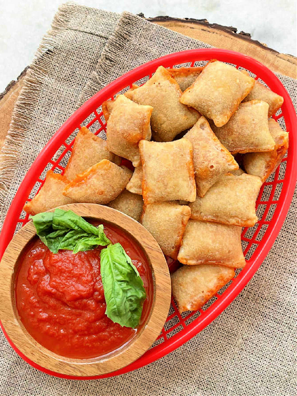 freshly air fried pizza rolls in a red snack basket and a side of marinara sauce