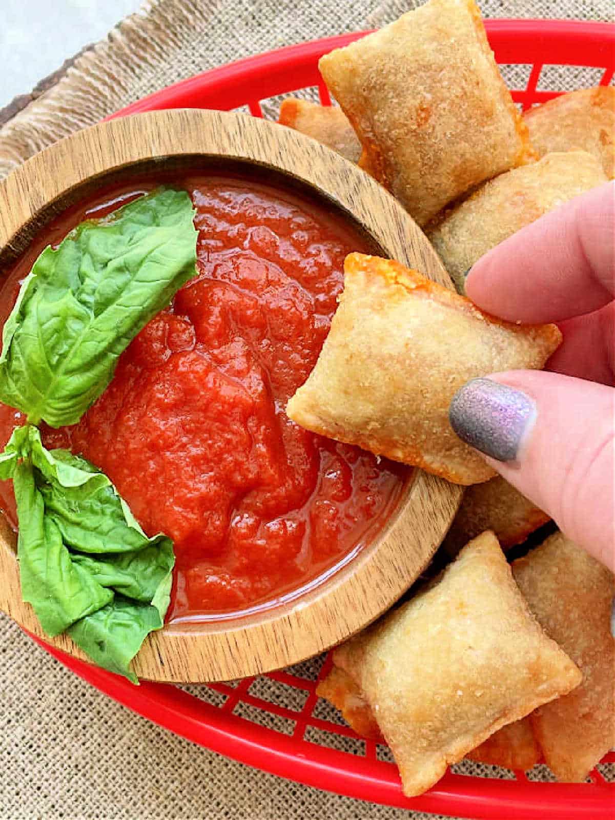 dipping an air fryer pizza roll into a small bowl of tomato sauce