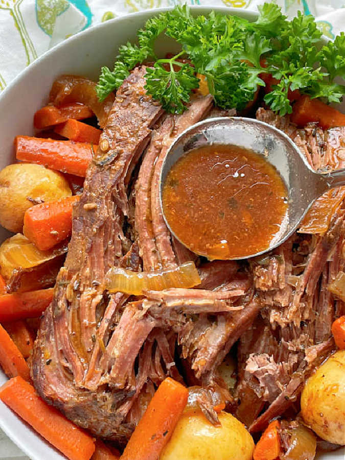 a ladle of au jus being poured over the tender sirloin tip pot roast