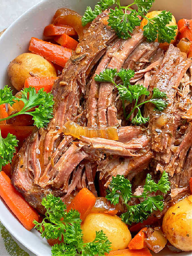close up view of tender pot roast surrounded by potatoes, carrots and onions