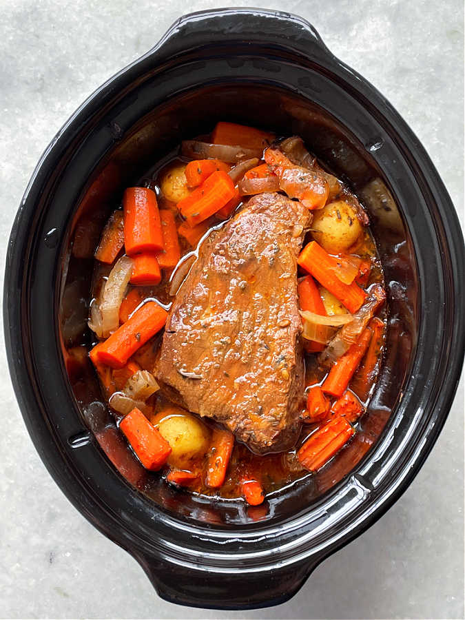showing the fully cooked beef roast in the crock pot insert
