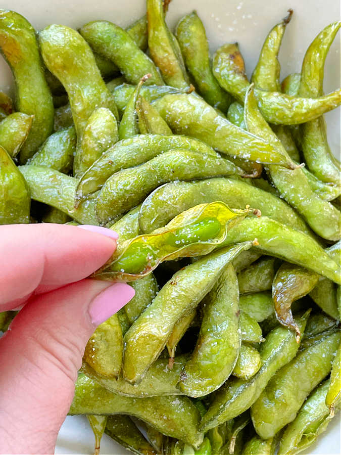 holding an opened edamame pod