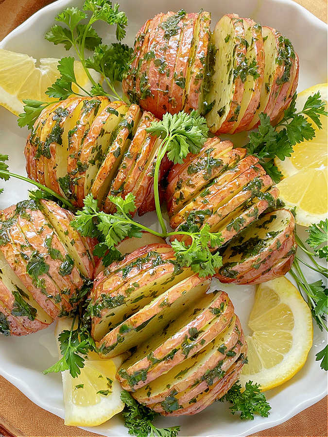 air fryer hasselback potatoes on a plate with parsley and lemon slices