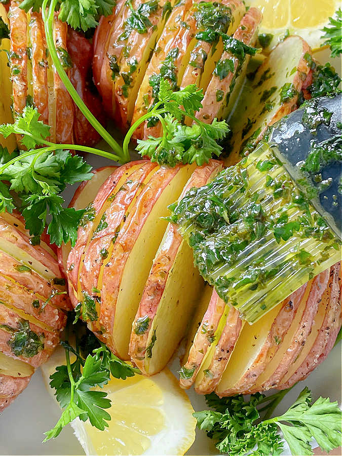 brushing parsley butter on air fried hasselback potatoes