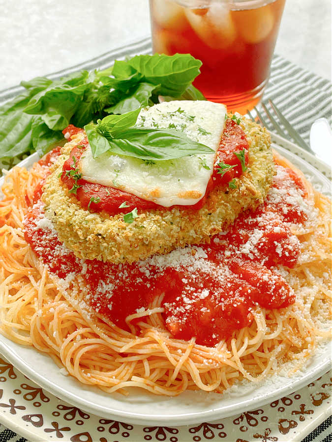 a plate of air fryer chicken parmesan with a glass of iced tea