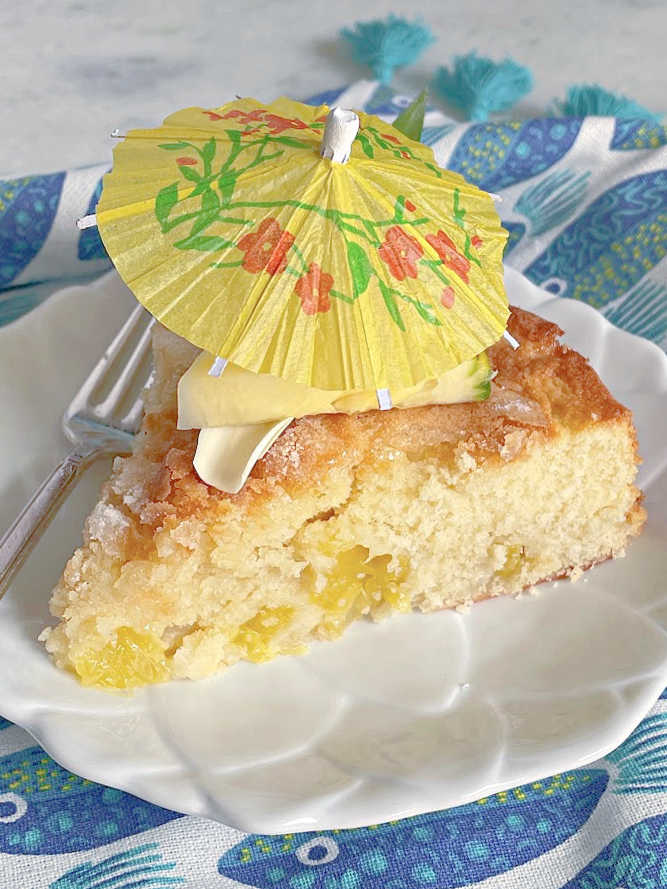 a slice of french pineapple cake topped with a cocktail umbrella